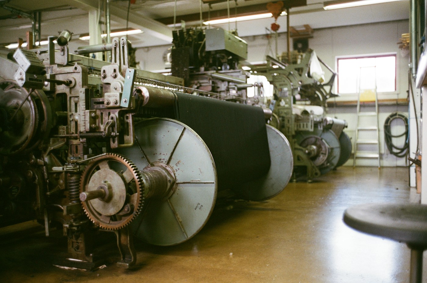 A row of industrial looms in the weaving shed